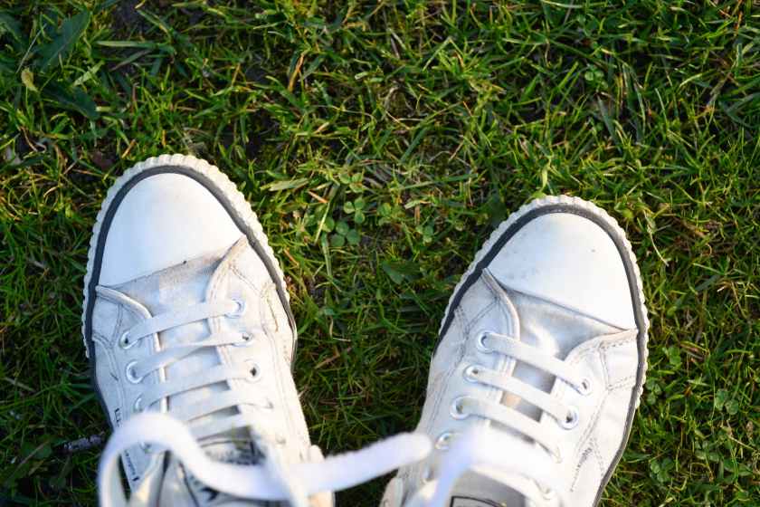 pair of white lace up sneakers on top green grass